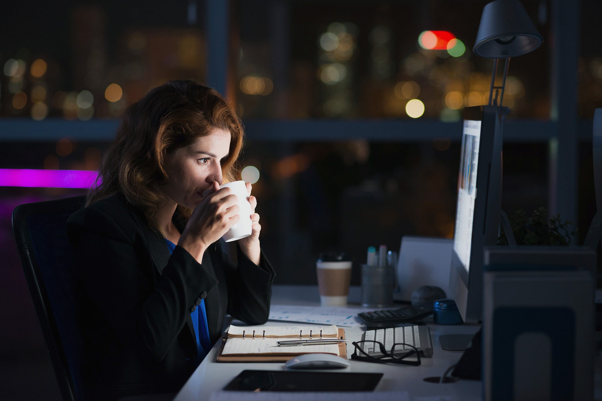 woman sipping coffee while working on computer